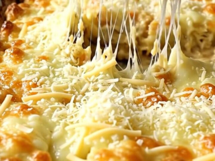 A top-down view of thick green cabbage wedges in a ceramic dish topped with melted mozzarella and parmesan cheese.