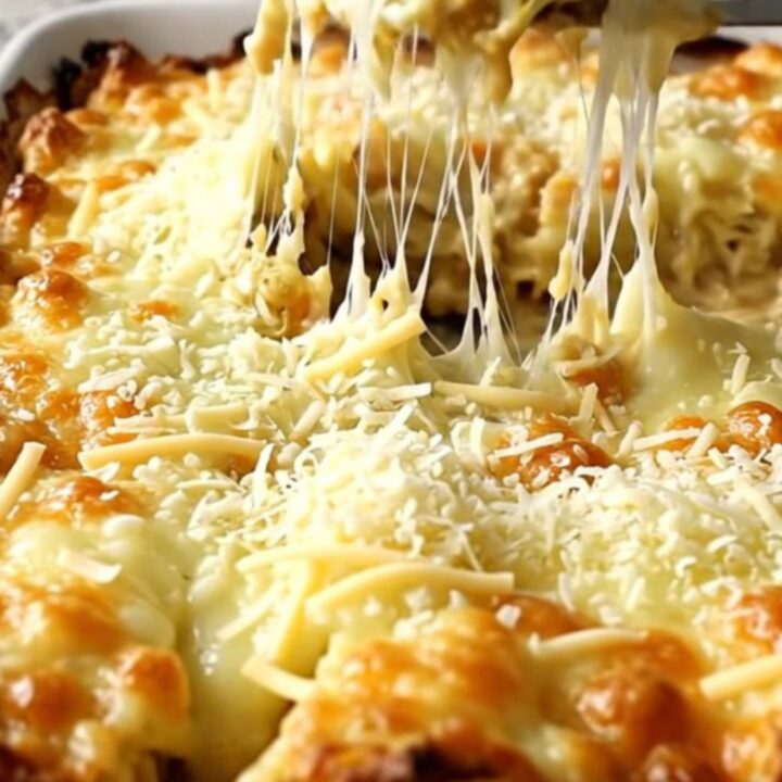 A top-down view of thick green cabbage wedges in a ceramic dish topped with melted mozzarella and parmesan cheese.