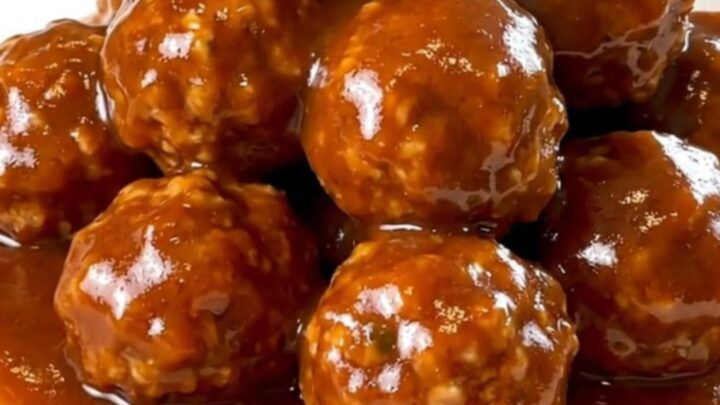 A slow cooker filled with turkey meatballs coated in a glossy, dark red maple sriracha sauce.