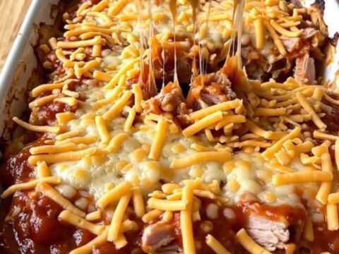 A large rectangular ceramic dish filled with a baked turkey and pasta sloppy joe casserole topped with melted cheddar cheese.