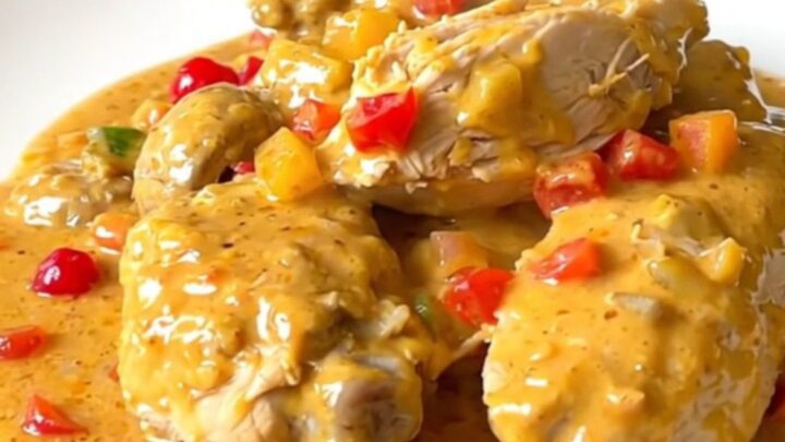 A close-up view of creamy chicken Newburg served on a white plate with visible mushrooms and pimentos.