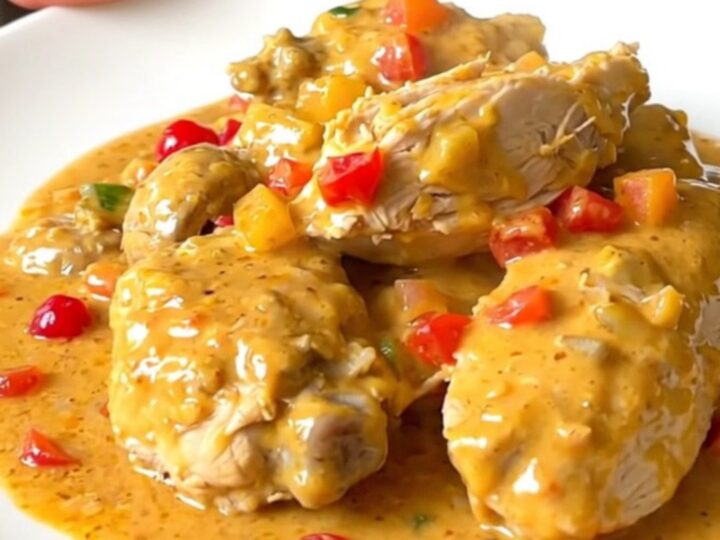 A close-up view of creamy chicken Newburg served on a white plate with visible mushrooms and pimentos.
