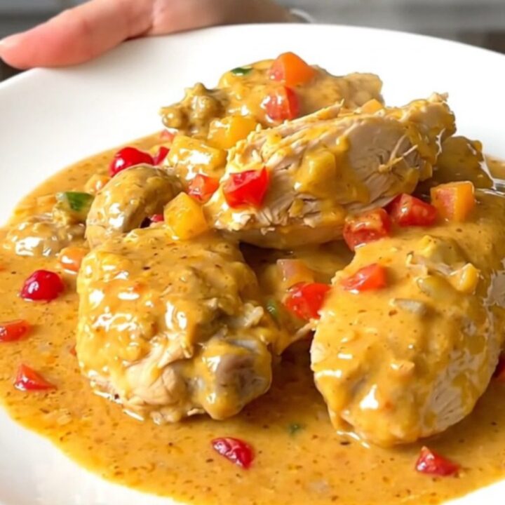 A close-up view of creamy chicken Newburg served on a white plate with visible mushrooms and pimentos.