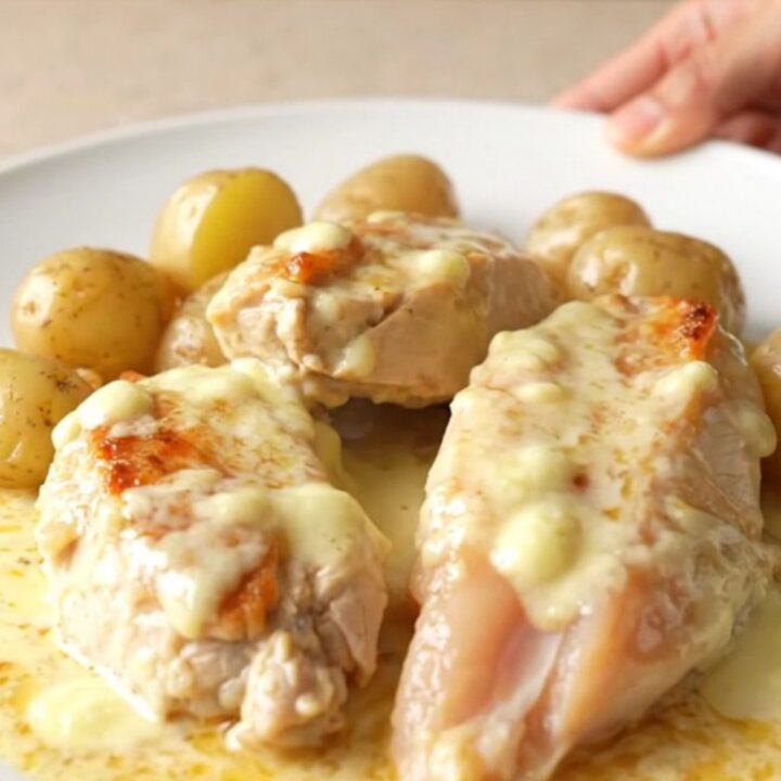 A high-angle shot showing tender chicken breasts and halved baby potatoes covered in a rich