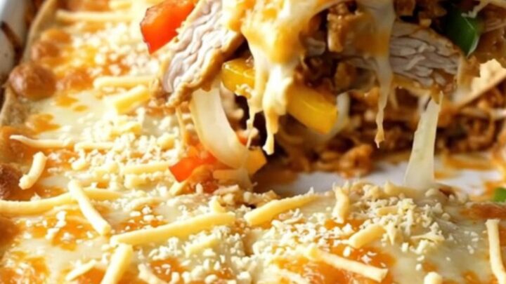 A large rectangular baking dish filled with a golden, bubbly chicken fajita tortilla bake on a wooden table.