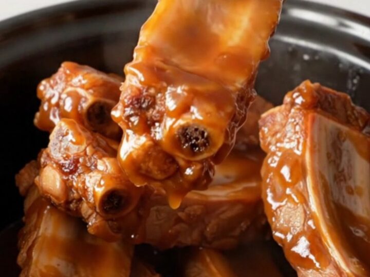 A bowl of slow-cooked boneless spareribs glazed in a rich, dark red-brown sauce.