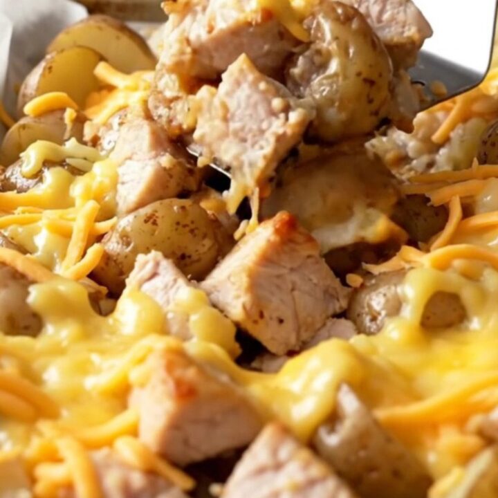 A sheet pan filled with roasted chicken chunks and baby potatoes topped with melted cheddar cheese.