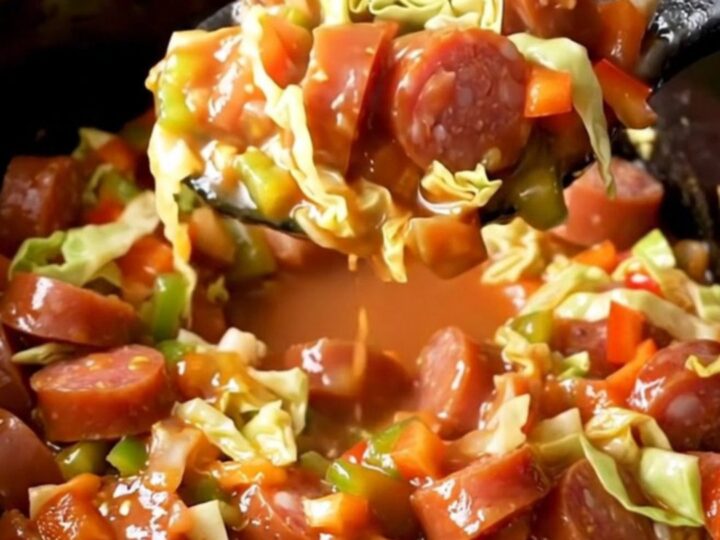 A close-up of the slow cooker filled with tender green cabbage, red and green bell peppers
