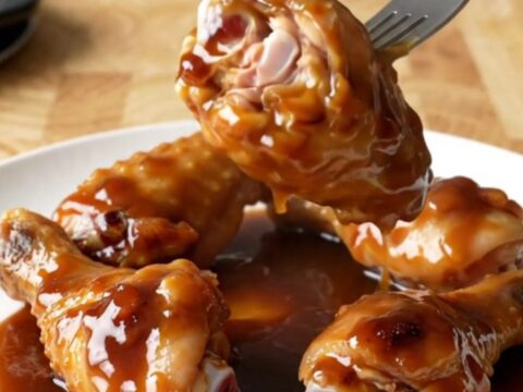 A close-up of mahogany-glazed chicken wings in a slow cooker, looking tender and sticky.