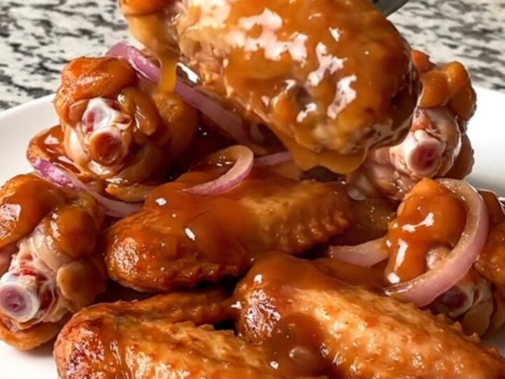 A platter of slow-cooked chicken wings coated in a glossy, dark reddish-brown maple chipotle glaze.