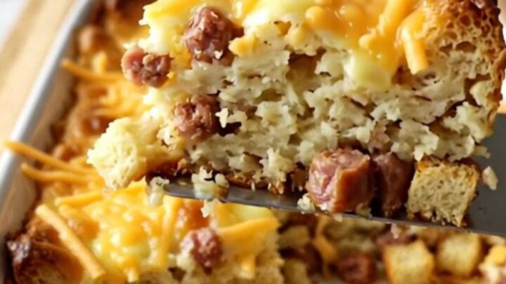 A golden, puffed breakfast casserole in a ceramic dish, topped with melted sharp cheddar cheese.