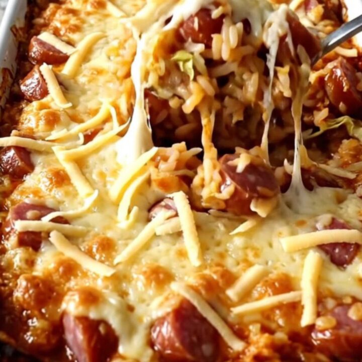 A top-down view of a rectangular baking dish filled with layers of cabbage, rice, kielbasa, and melted Swiss cheese.