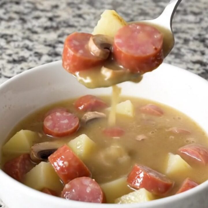 A bowl of creamy kielbasa stroganoff soup featuring sliced sausage, mushrooms, and gold potatoes in a rich, creamy broth.