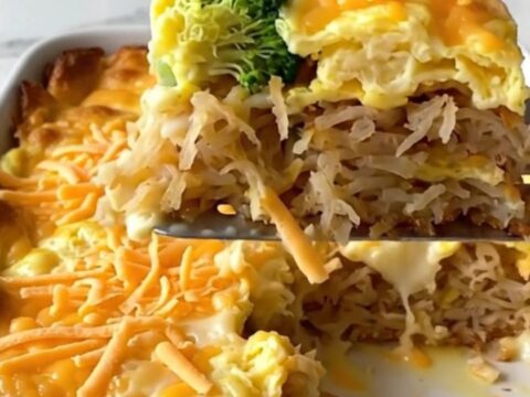 A golden, bubbling broccoli cheddar hash brown egg bake in a white ceramic dish on a quartz countertop.