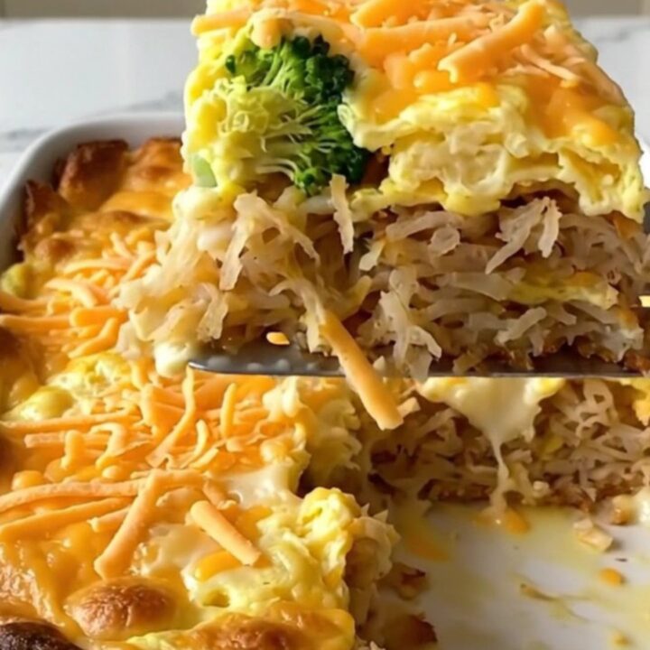 A golden, bubbling broccoli cheddar hash brown egg bake in a white ceramic dish on a quartz countertop.