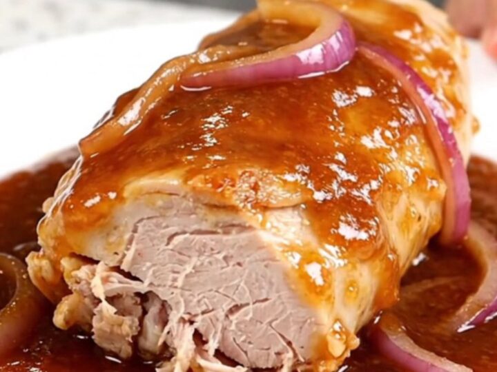 Slow cooked honey chipotle turkey tenderloin served on a white plate with red onions.