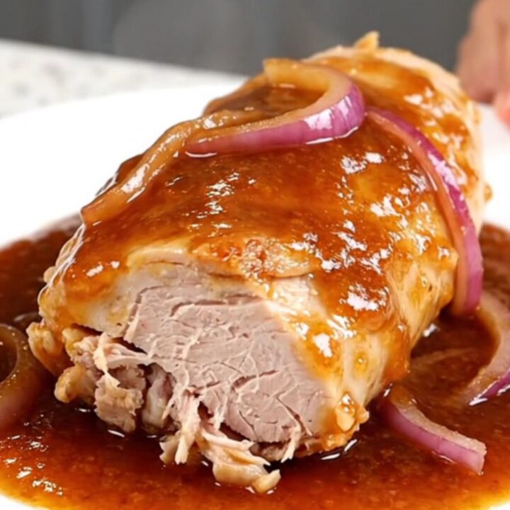 Slow cooked honey chipotle turkey tenderloin served on a white plate with red onions.