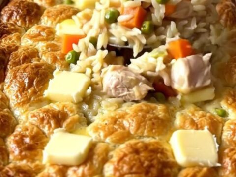A top-down view of a creamy chicken pot pie rice bake in a white ceramic dish.