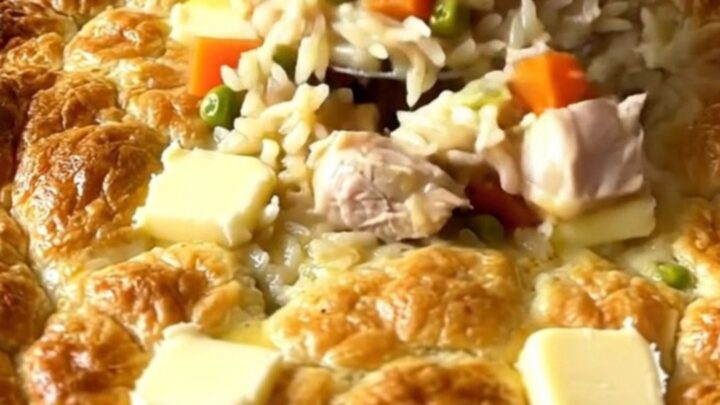 A top-down view of a creamy chicken pot pie rice bake in a white ceramic dish.