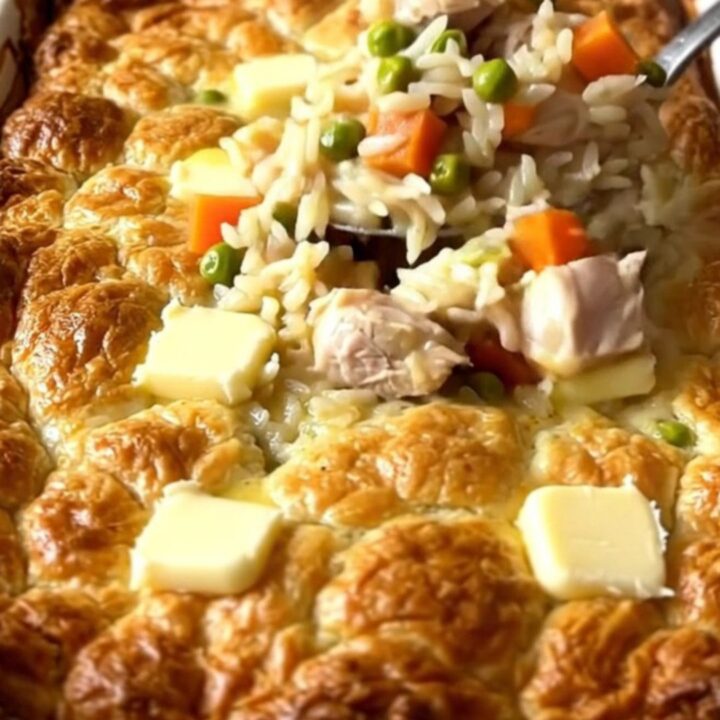 A top-down view of a creamy chicken pot pie rice bake in a white ceramic dish.