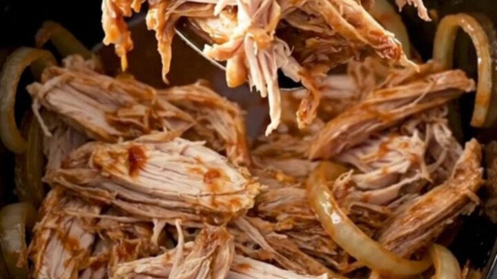A close-up of shredded smoky chipotle turkey sliders on soft buns, garnished with fresh herbs.