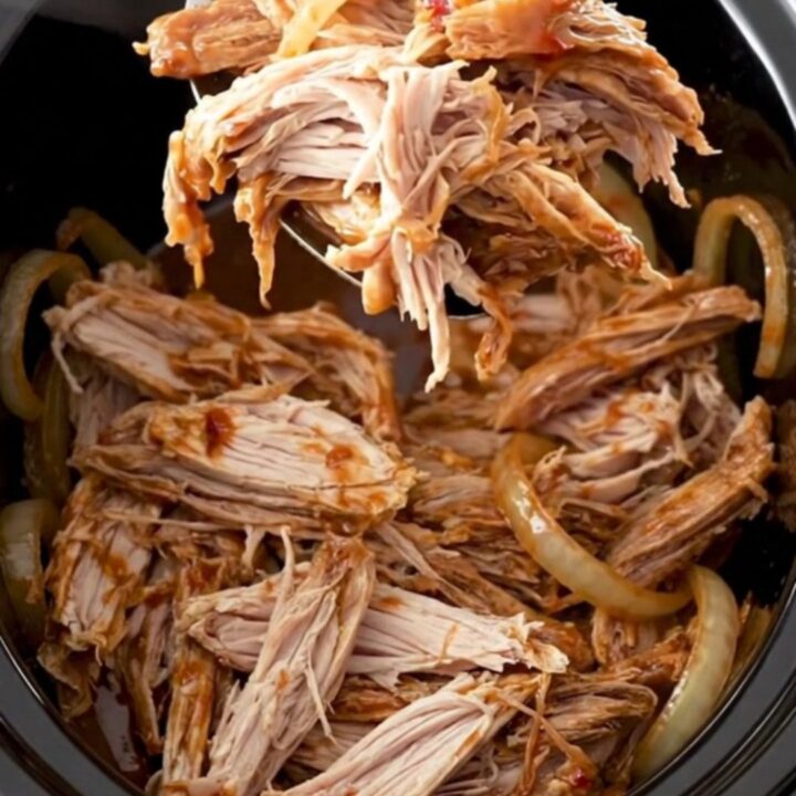 A close-up of shredded smoky chipotle turkey sliders on soft buns, garnished with fresh herbs.