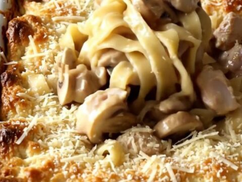 A top-down view of a rectangular baker filled with creamy Chicken Marsala and egg noodles.