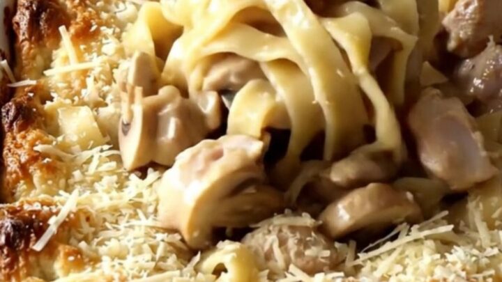 A top-down view of a rectangular baker filled with creamy Chicken Marsala and egg noodles.