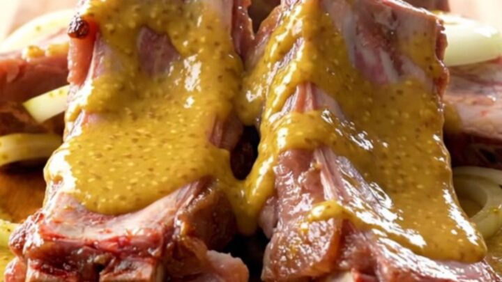 A ceramic slow cooker insert filled with tender pork spareribs coated in a thick, golden honey mustard sauce.