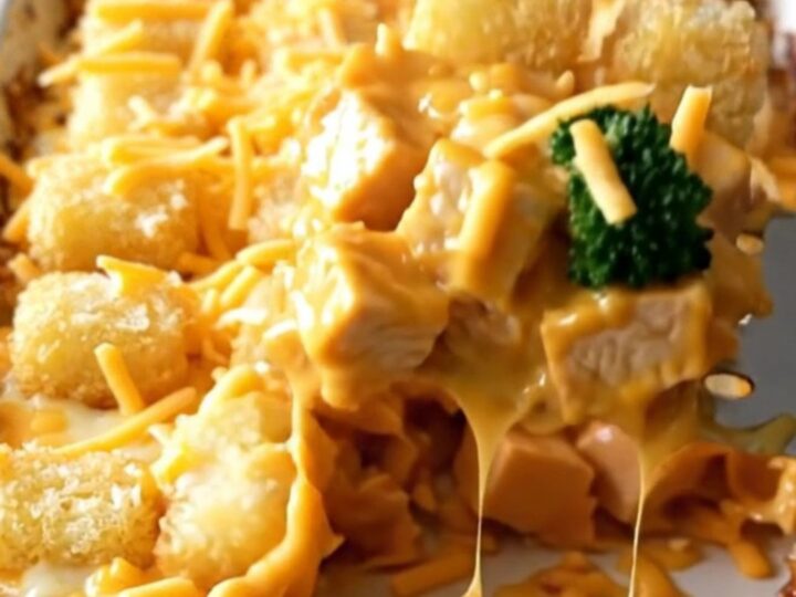 A golden, bubbling broccoli cheddar chicken bake in a white ceramic dish.