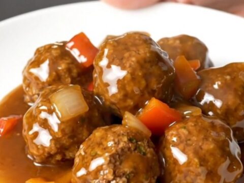 A plate of Crockpot Cajun Honey Turkey Meatballs glazed in a thick, shiny sauce with visible pieces of peppers and onions.