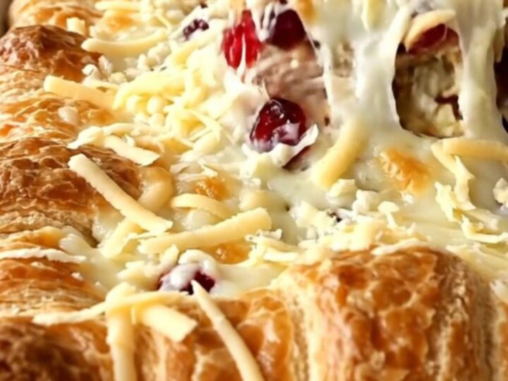 A golden-brown turkey and cranberry crescent bake in a white baking dish on a white quartz counter.