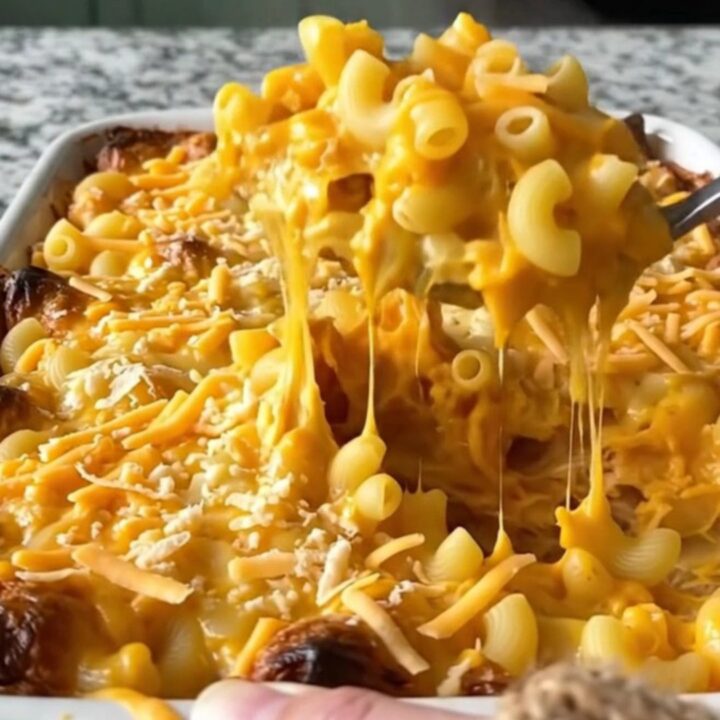 A top-down view of a creamy butternut squash mac and cheese bake in a ceramic dish, covered in golden melted sharp cheddar.
