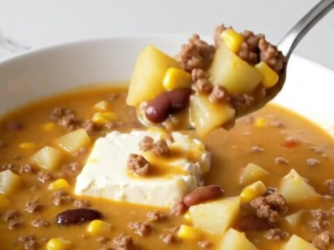 A steaming bowl of creamy cowgirl soup filled with ground beef, potato cubes, black beans, and yellow corn.