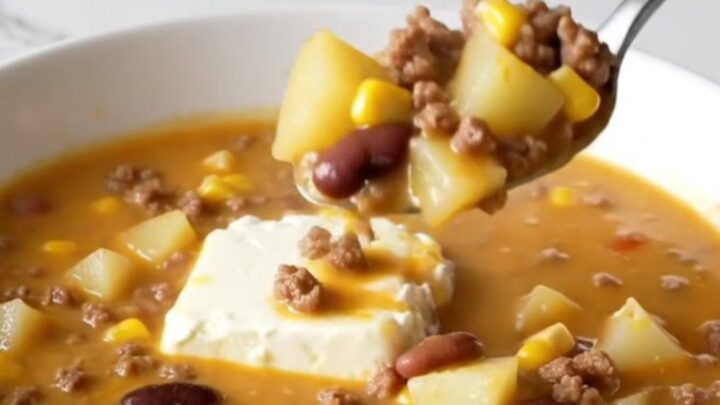 A steaming bowl of creamy cowgirl soup filled with ground beef, potato cubes, black beans, and yellow corn.