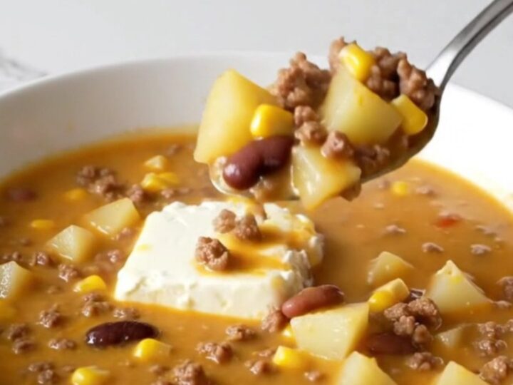 A steaming bowl of creamy cowgirl soup filled with ground beef, potato cubes, black beans, and yellow corn.