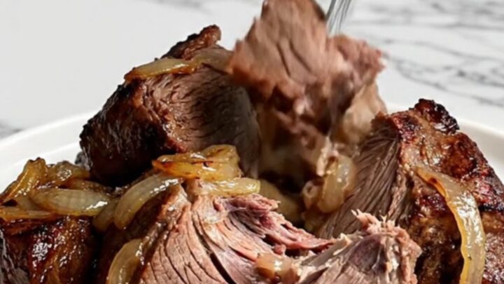 A rustic slow cooker pot roast featuring tender beef chuck, halved baby potatoes, and vibrant green beans in savory juices.