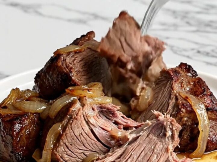 A rustic slow cooker pot roast featuring tender beef chuck, halved baby potatoes, and vibrant green beans in savory juices.