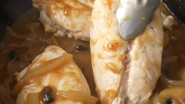 A close-up of tender, cooked Salisbury chicken breasts smothered in a rich