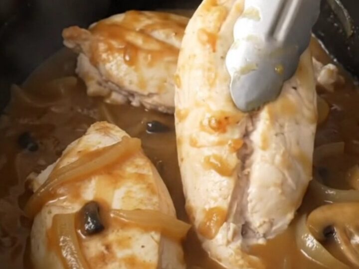 A close-up of tender, cooked Salisbury chicken breasts smothered in a rich