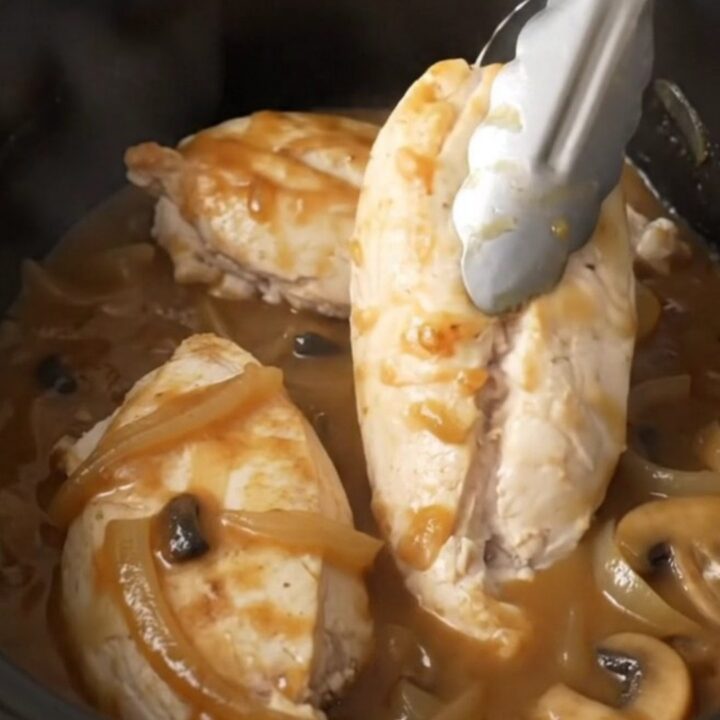 A close-up of tender, cooked Salisbury chicken breasts smothered in a rich