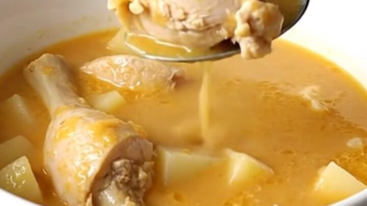 A bowl of creamy cheddar chicken and potato soup with visible chunks of chicken and potato, garnished with fresh parsley.