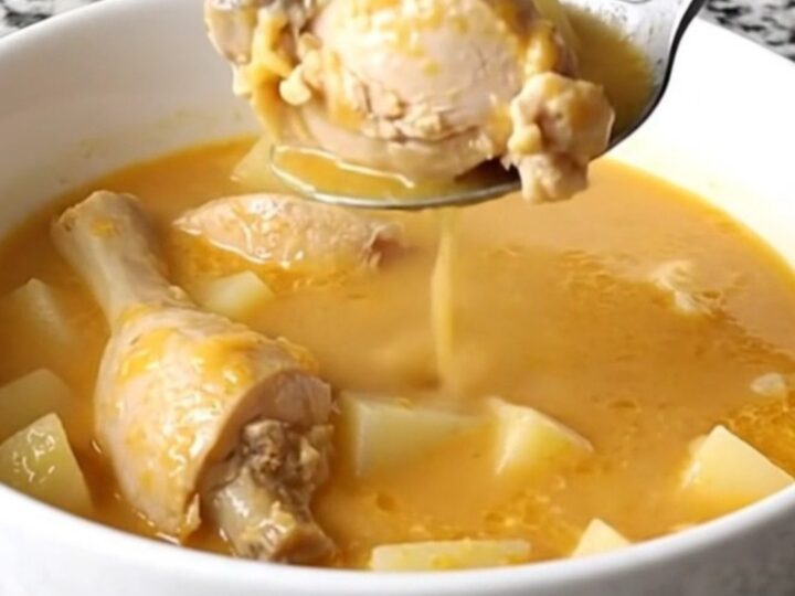 A bowl of creamy cheddar chicken and potato soup with visible chunks of chicken and potato, garnished with fresh parsley.