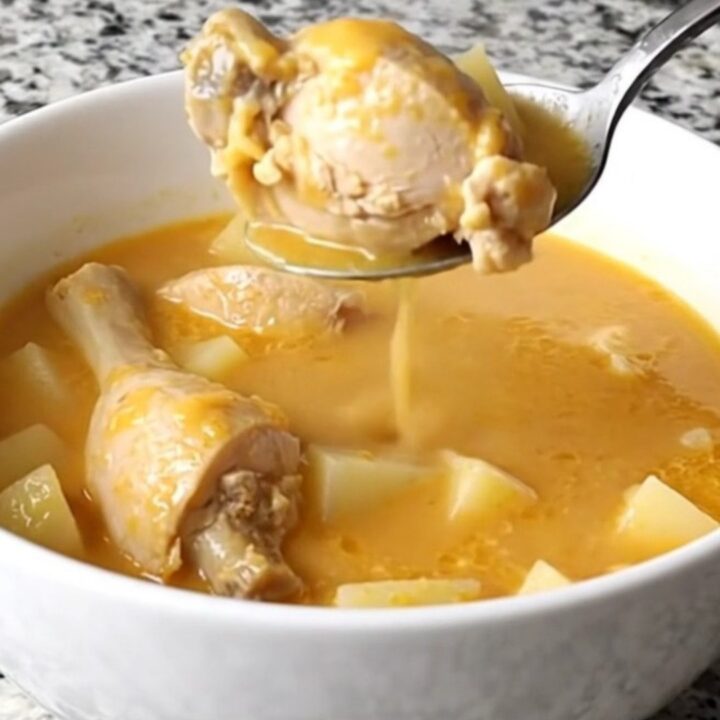 A bowl of creamy cheddar chicken and potato soup with visible chunks of chicken and potato, garnished with fresh parsley.