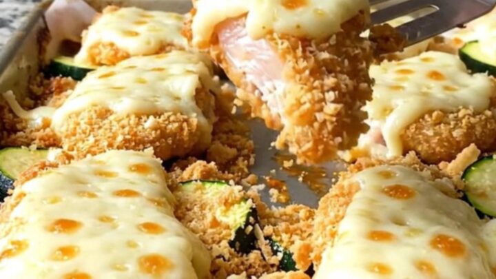 Crispy baked chicken parmesan tenders with melted cheese and tender zucchini on a sheet pan.