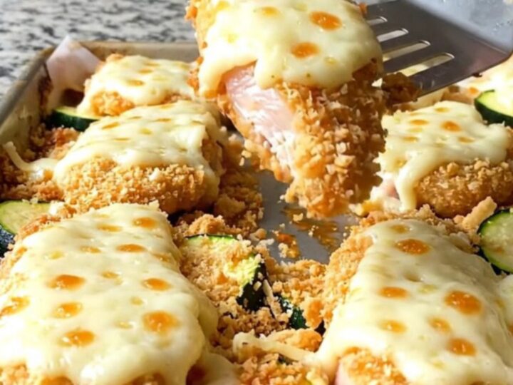 Crispy baked chicken parmesan tenders with melted cheese and tender zucchini on a sheet pan.