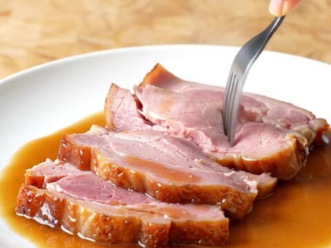 A spiral-sliced bone-in ham in a slow cooker, glazed with brown sugar and pepper soda.