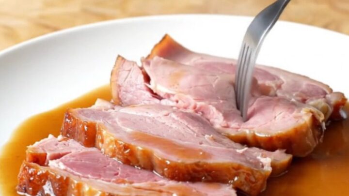 A spiral-sliced bone-in ham in a slow cooker, glazed with brown sugar and pepper soda.