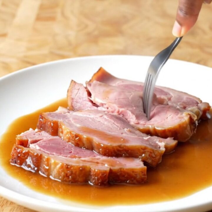 A spiral-sliced bone-in ham in a slow cooker, glazed with brown sugar and pepper soda.