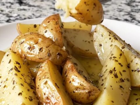 A close-up of tender golden potato wedges in a slow cooker, seasoned with herbs and lemon.